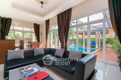 Luxurious living room with pool view and elegant black sofa in a modern home.