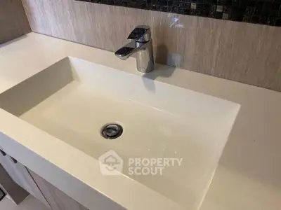Modern bathroom sink with sleek faucet and elegant tile backsplash.