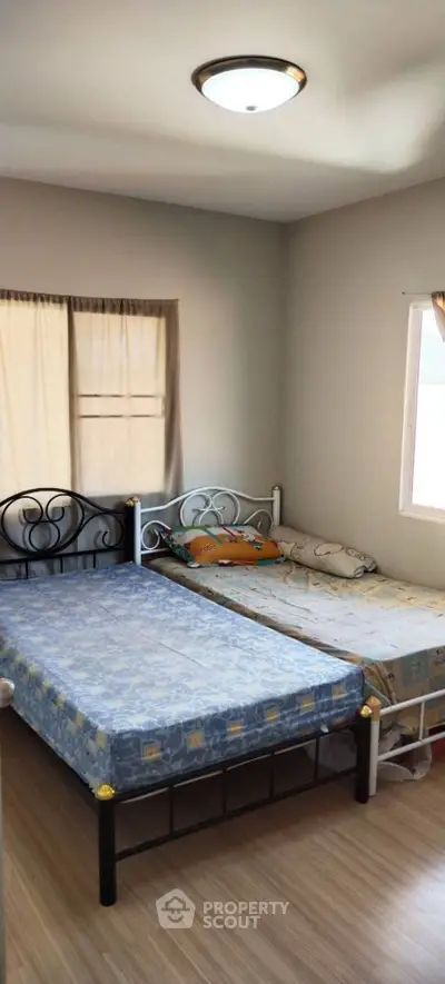 Cozy bedroom with twin beds and natural light, perfect for small families or shared living.