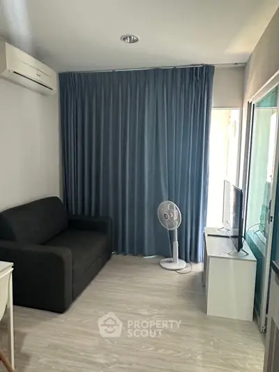 Cozy living room with modern sofa, TV, and air conditioning, ideal for relaxation.