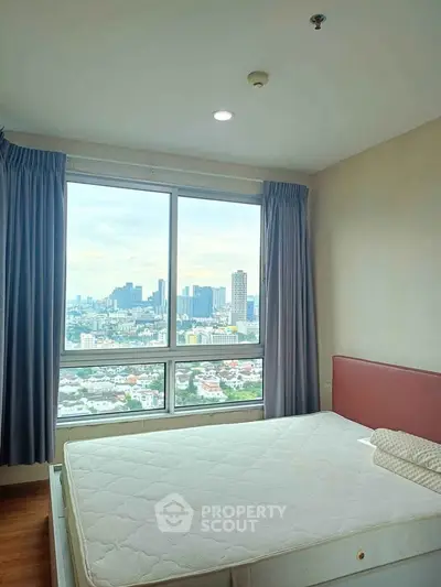 Spacious bedroom with city view from large window in high-rise apartment