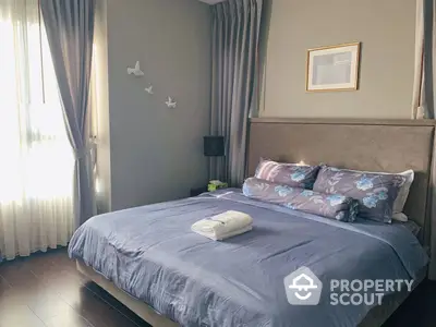 Serene bedroom with natural light streaming through sheer curtains, featuring a plush bed with stylish linens and tasteful wall art.