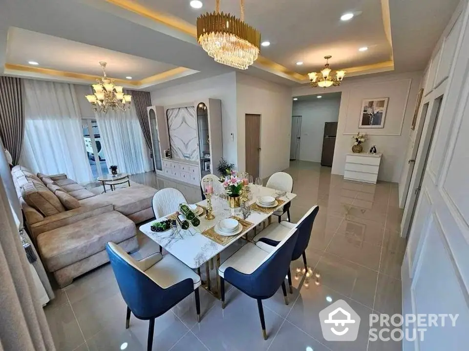 Luxurious open-plan living and dining area with elegant chandelier and modern decor.