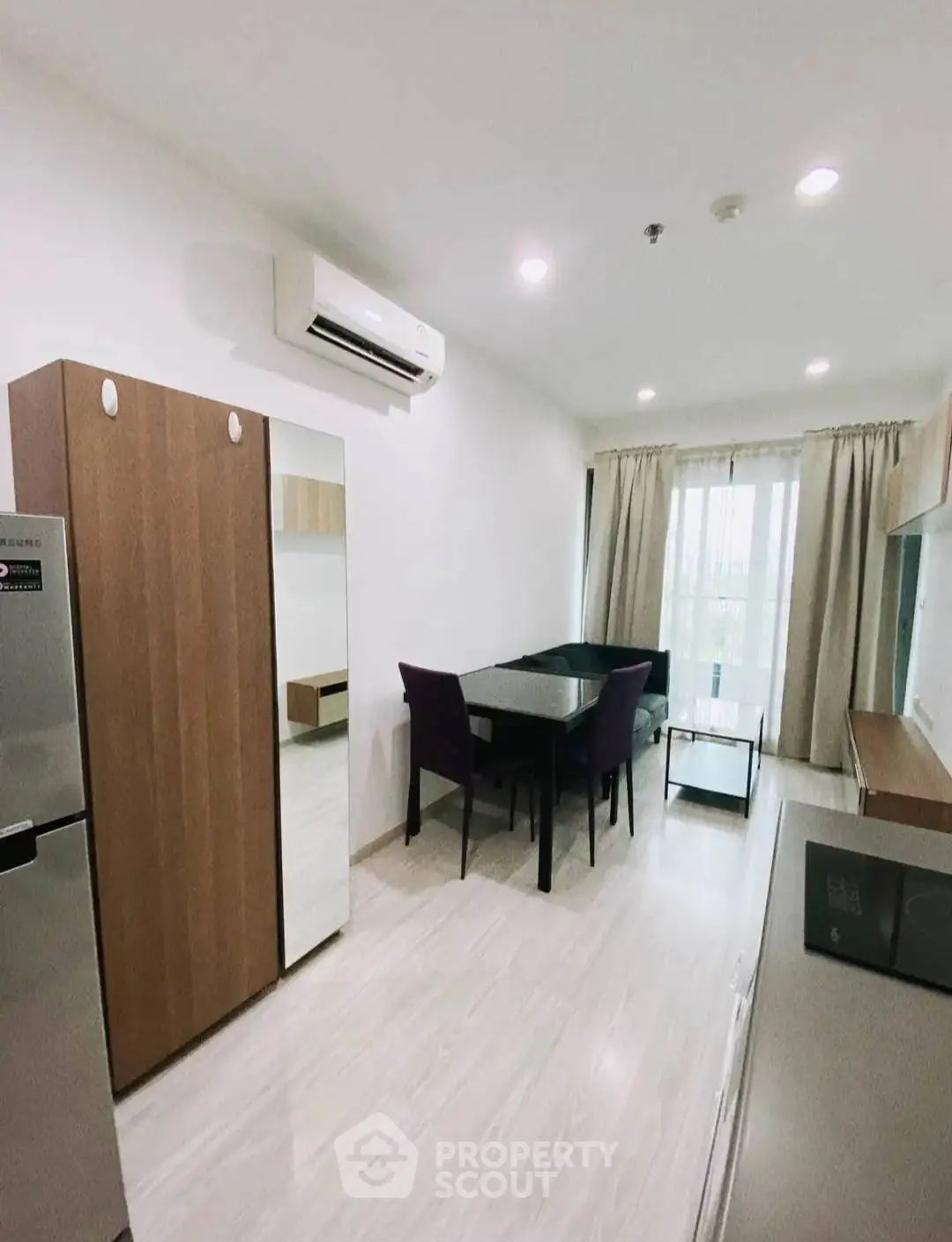 Modern living room with dining area and natural light, featuring sleek furniture and air conditioning.