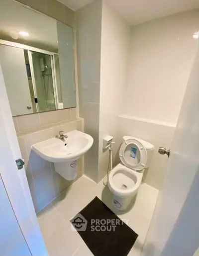 Modern bathroom with sleek fixtures and neutral tiles, featuring a compact layout and contemporary design.