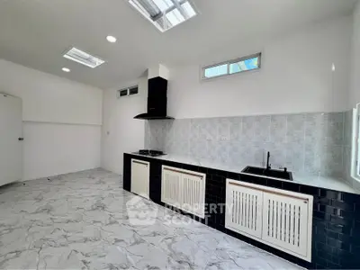 Spacious modern kitchen with sleek black and white design, featuring gas stove and ample natural light.