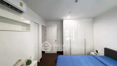 Modern bedroom with sleek white wardrobe and blue bedding, featuring air conditioning and minimalist decor.