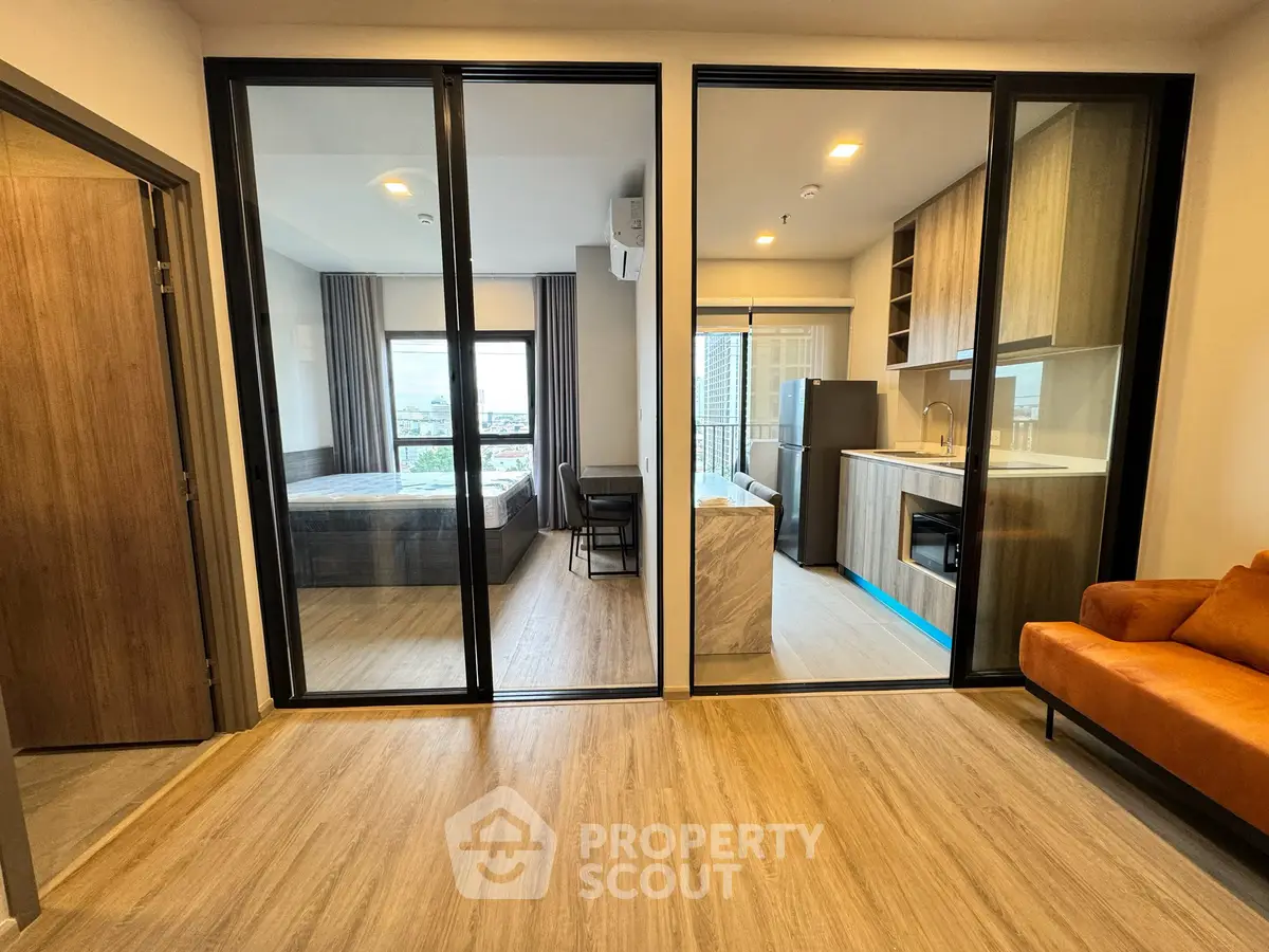 Modern apartment interior with glass partitions, cozy living area, and sleek kitchen design.