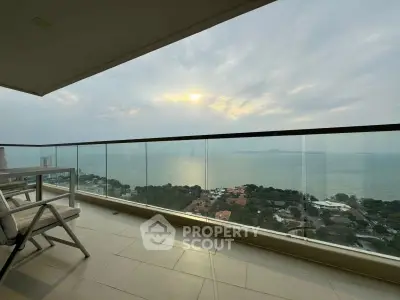 Stunning ocean view from a high-rise balcony with glass railing and seating area.