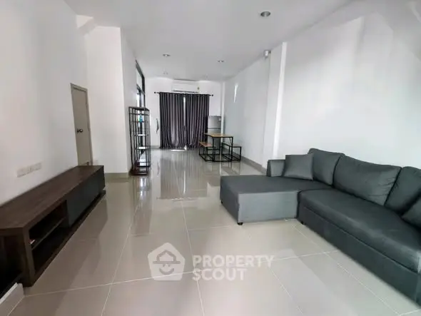 Spacious modern living room with sleek gray sofa and elegant tile flooring.