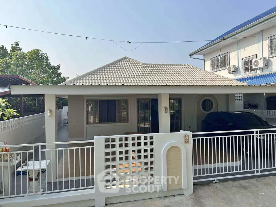 Charming single-story house with tiled roof and gated driveway in a serene neighborhood.