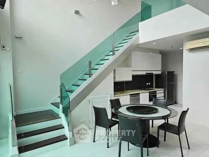 Modern duplex with sleek glass staircase and stylish dining area