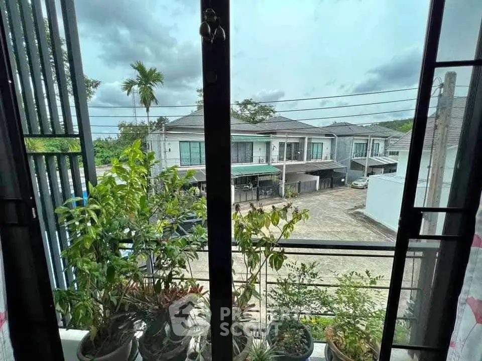 Charming view from a window overlooking modern townhouses and lush greenery.