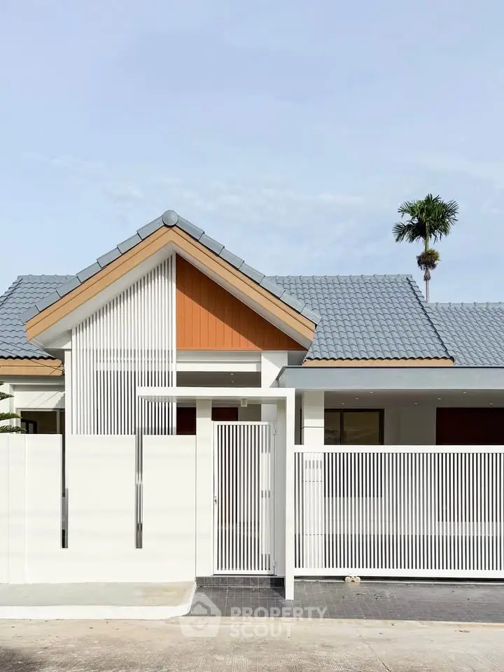 Modern single-story house with sleek design and gated entrance, featuring a stylish roof and minimalist facade.