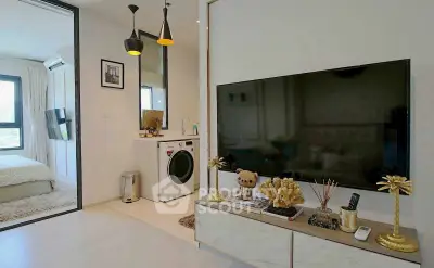 Modern living room with large TV, stylish decor, and adjacent bedroom view.