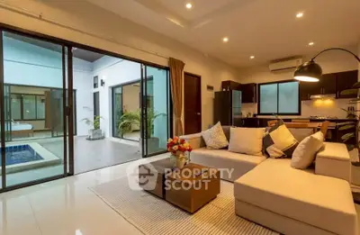 Luxurious open-plan living room with modern kitchen and pool view, perfect for entertaining.