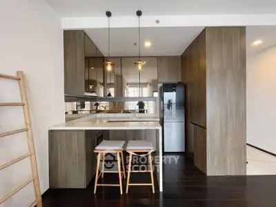 Modern kitchen with sleek wooden cabinets and stylish bar stools in a contemporary apartment.