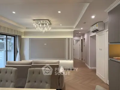 Elegant living room with modern chandelier and neutral decor in a stylish apartment.