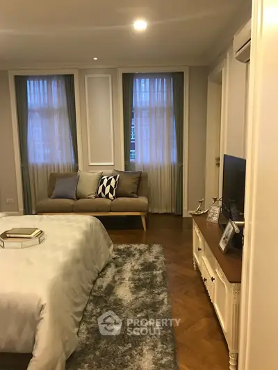 Elegant bedroom with cozy sofa and stylish decor, featuring soft lighting and a plush rug for a warm ambiance.