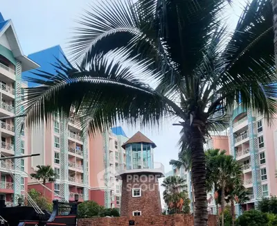 Tropical resort-style apartment complex with palm trees and unique architectural features.