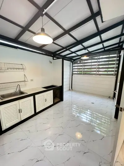 Modern kitchen with sleek black and white design, featuring open layout and ample natural light.