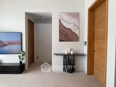 Modern living room with stylish decor and wooden doors, featuring a large TV and elegant artwork.
