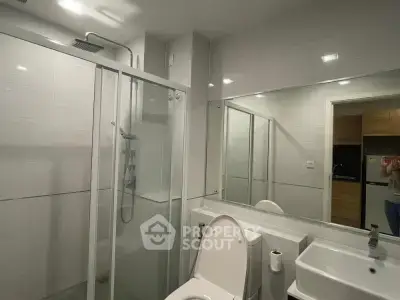 Modern bathroom with glass shower and sleek fixtures in contemporary apartment.