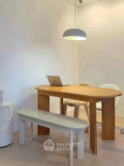 Modern study room with wooden table, chairs, and pendant light, perfect for productivity and style.