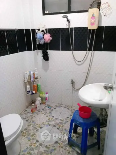 Compact bathroom with shower, sink, and toilet in modern tiled design.