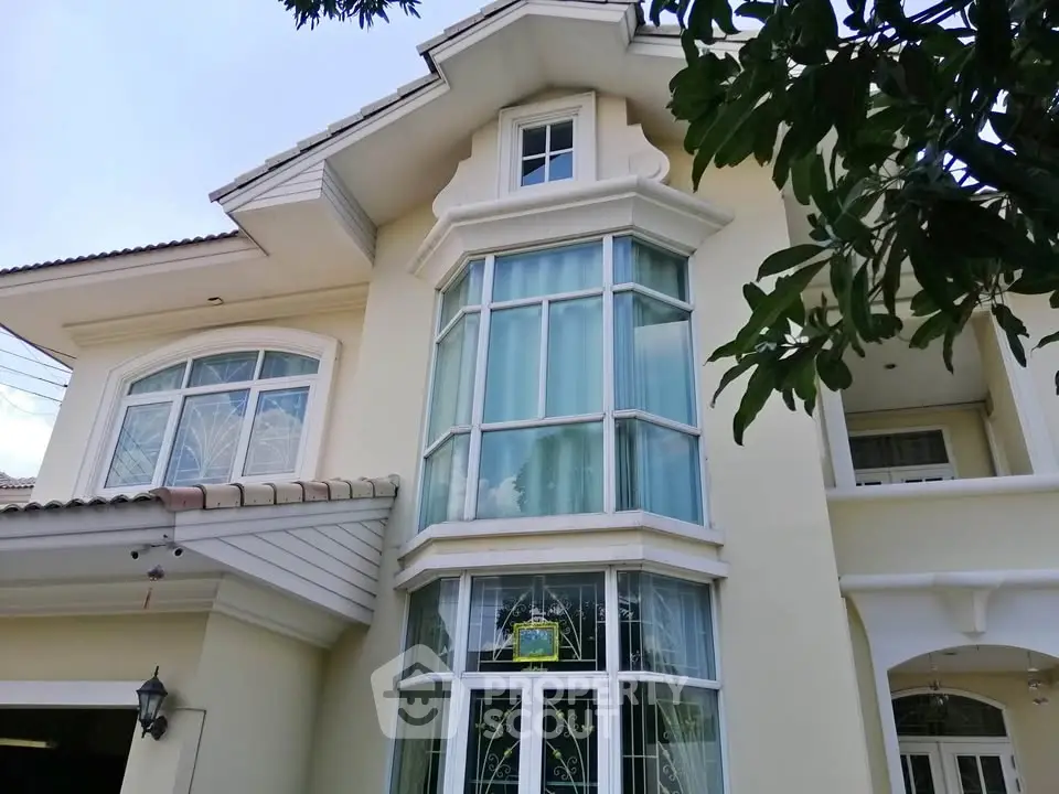 Elegant two-story house with large bay windows and cream exterior, showcasing modern architectural design.