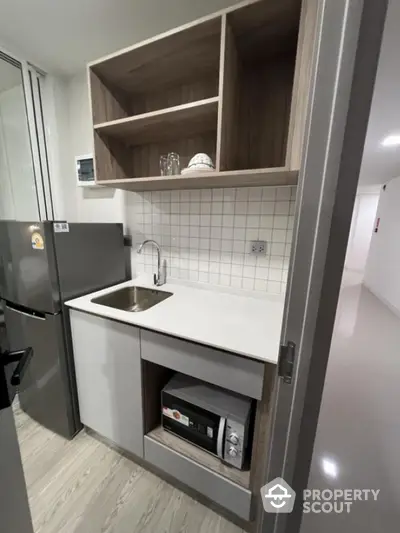 Modern compact kitchen with sleek cabinetry, stainless steel appliances, and stylish tile backsplash.