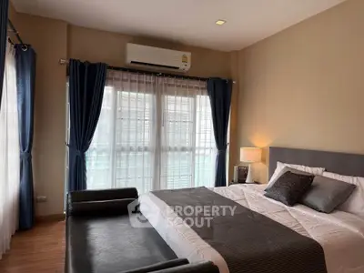 Elegant bedroom with large windows and modern decor, featuring a cozy bed and stylish curtains.