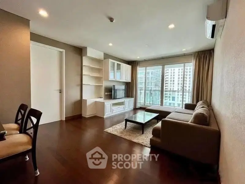 Spacious living room with modern furniture and large windows offering city views.