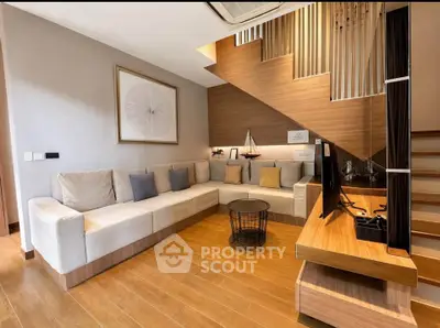 Modern living room with stylish decor and wooden flooring, featuring a cozy sectional sofa and sleek TV setup.
