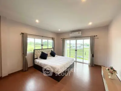 Spacious bedroom with large windows and scenic view, featuring modern decor and ample natural light.