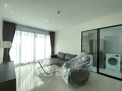 Modern living room with large windows, sleek furniture, and natural light.