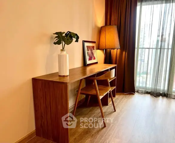 Stylish study area with wooden desk and chair, modern lamp, and city view.