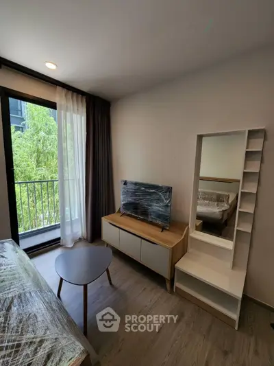 Modern living room with balcony view, featuring sleek furniture and natural light.