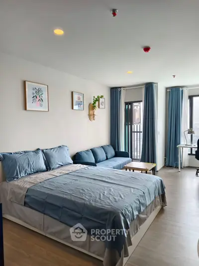 Spacious bedroom with modern decor and natural light, featuring a cozy seating area and stylish furnishings.