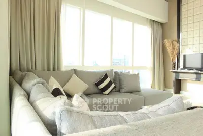 Spacious living room with modern gray sectional sofa and large windows offering ample natural light.