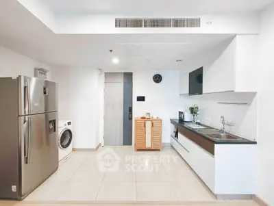 Modern kitchen with sleek appliances and open layout, featuring a washing machine and stainless steel fridge.