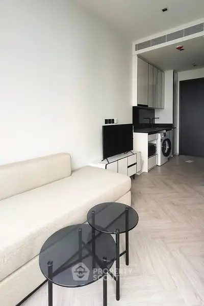 Modern living room with sleek furniture and integrated kitchen appliances in a stylish apartment.