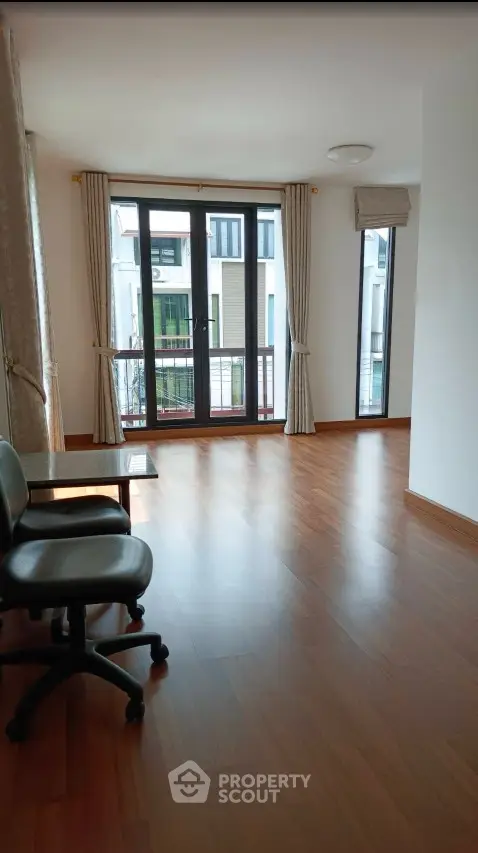 Spacious room with wooden flooring and large windows offering ample natural light.