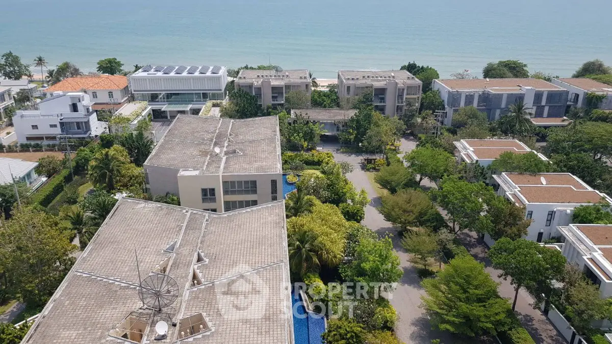 Stunning aerial view of beachfront villas with lush greenery and ocean backdrop, perfect for luxury living.