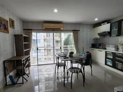 Modern open-layout kitchen and dining area with balcony view, featuring sleek appliances and stylish furniture.