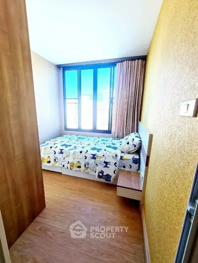 Cozy bedroom with large window and wooden flooring, perfect for natural light lovers.