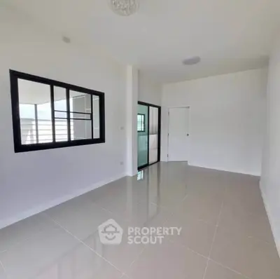 Spacious empty room with glossy tiled floor and large windows, perfect for customization.