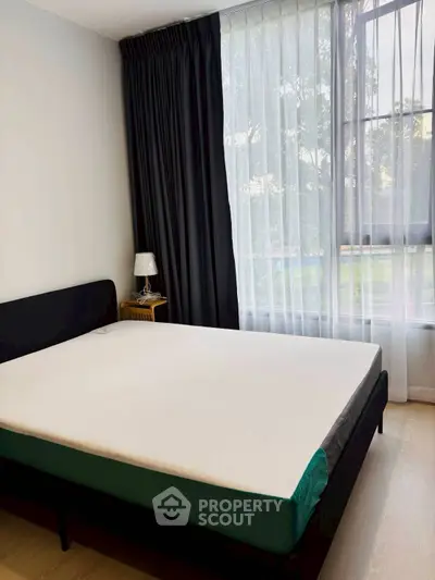 Modern bedroom with large window and stylish curtains in a cozy apartment.