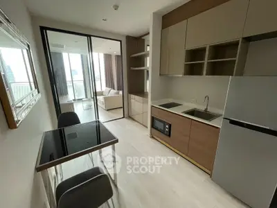 Modern open-layout kitchen with sleek appliances and dining area, leading to a bright living room with balcony view.