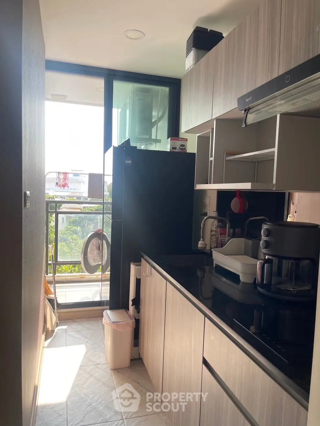 Modern kitchen with sleek cabinetry and appliances, featuring a balcony view.